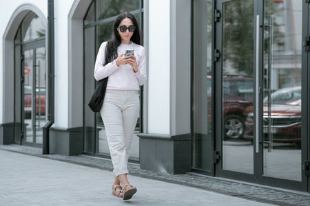 Gorgeous young woman in fashion clothes walk at the street. Attractive girl model in casual outfit walk on city street near vintage building. side view.の写真素材