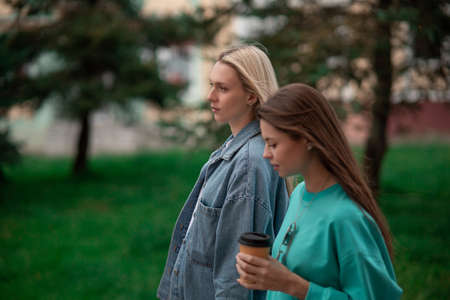 Two cool fashionable pregnant girlfriends in fashionable clothes are walking down the street and talking. Friends share secrets and discuss the birth of children.の写真素材