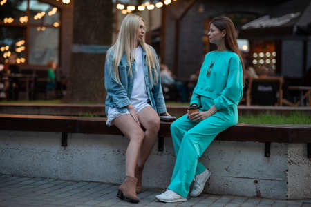Positive pregnant girls in fashionable clothes talk and have a good time. Attractive happy girls socialize outdoors. Preparation for the birth of a child.の写真素材