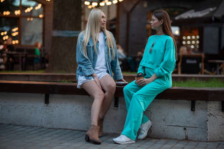 Positive pregnant girls in fashionable clothes talk and have a good time. Attractive happy girls socialize outdoors. Preparation for the birth of a child.の写真素材