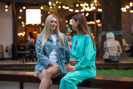 Positive pregnant girls in fashionable clothes talk and have a good time. Attractive happy girls socialize outdoors. Preparation for the birth of a child.の写真素材