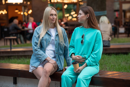Positive pregnant girls in fashionable clothes talk and have a good time. Attractive happy girls socialize outdoors. Preparation for the birth of a child.の写真素材