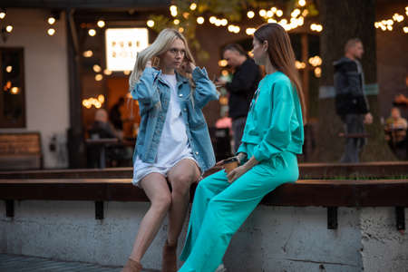 Positive pregnant girls in fashionable clothes talk and have a good time. Attractive happy girls socialize outdoors. Preparation for the birth of a child.の写真素材