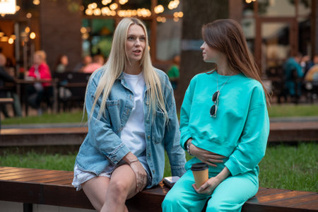 Positive pregnant girls in fashionable clothes talk and have a good time. Attractive happy girls socialize outdoors. Preparation for the birth of a child.の写真素材