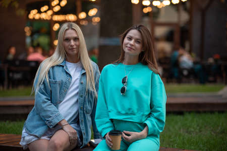 Positive pregnant girls in fashionable clothes talk and have a good time. Attractive happy girls socialize outdoors. Preparation for the birth of a child.の写真素材