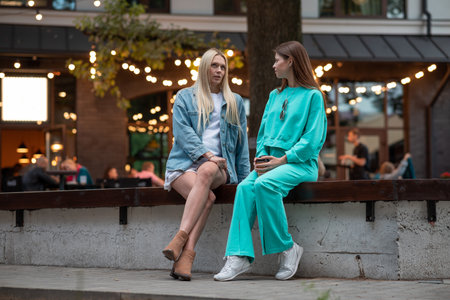 Positive pregnant girls in fashionable clothes talk and have a good time. Attractive happy girls socialize outdoors. Preparation for the birth of a child.の写真素材