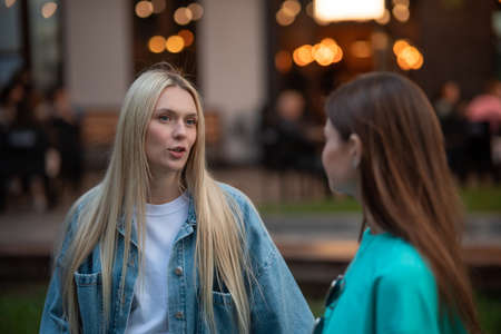 Positive pregnant girls in fashionable clothes talk and have a good time. Attractive happy girls socialize outdoors. Preparation for the birth of a child.の写真素材