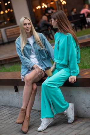 Positive pregnant girls in fashionable clothes talk and have a good time. Attractive happy girls socialize outdoors. Preparation for the birth of a child.の写真素材