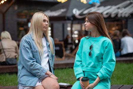 Positive pregnant girls in fashionable clothes talk and have a good time. Attractive happy girls socialize outdoors. Preparation for the birth of a child.の写真素材