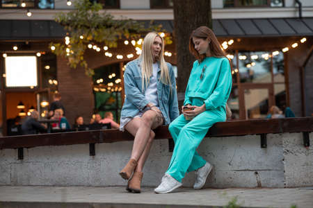 Positive pregnant girls in fashionable clothes talk and have a good time. Attractive happy girls socialize outdoors. Preparation for the birth of a child.の写真素材