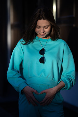 Portrait of a pretty attractive sexy young pregnant woman with natural makeup with beautiful eyes in a fashionable bright clothes. Girl is walking around the city.の写真素材