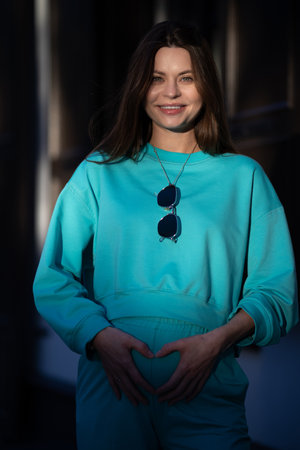 Portrait of a pretty attractive sexy young pregnant woman with natural makeup with beautiful eyes in a fashionable bright clothes. Girl is walking around the city.の写真素材