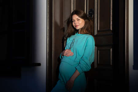 Portrait of a pretty attractive sexy young pregnant woman with natural makeup with beautiful eyes in a fashionable bright clothes. Girl is walking around the city.の写真素材