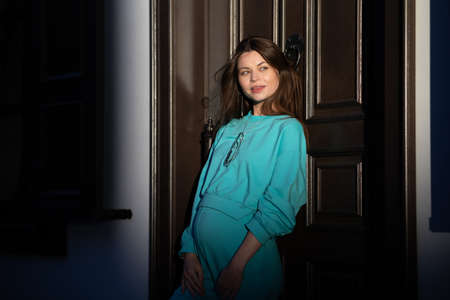 Portrait of a pretty attractive sexy young pregnant woman with natural makeup with beautiful eyes in a fashionable bright clothes. Girl is walking around the city.の写真素材