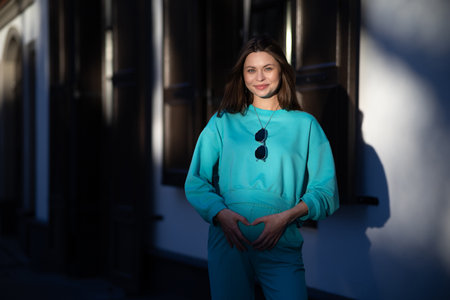 Portrait of a pretty attractive sexy young pregnant woman with natural makeup with beautiful eyes in a fashionable bright clothes. Girl is walking around the city.の写真素材