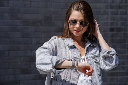 Fashionable women's portrait of a beautiful vogue girl pregnant model with fashion black eyewear in a stylish white short dress near a black brick wallの写真素材