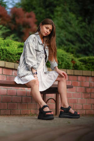 Gorgeous young pregnant woman in fashion jeans clothes in stylish dress has a good time in the park. Attractive girl model in casual outfit.の写真素材