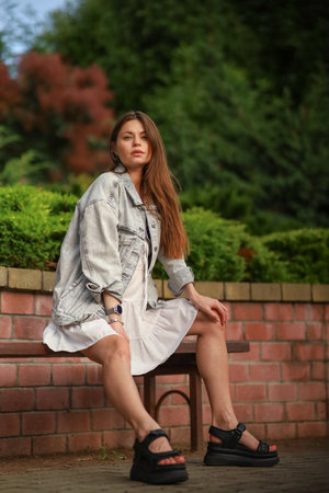 Gorgeous young pregnant woman in fashion jeans clothes in stylish dress has a good time in the park. Attractive girl model in casual outfit.の写真素材