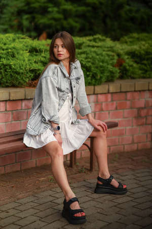 Gorgeous young pregnant woman in fashion jeans clothes in stylish dress has a good time in the park. Attractive girl model in casual outfit.の写真素材