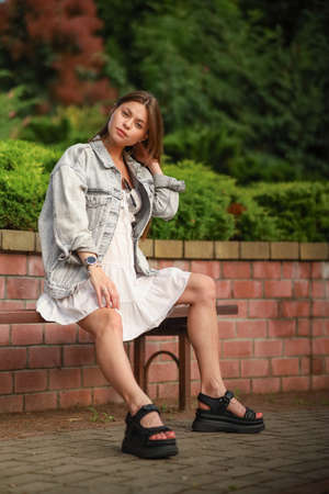 Gorgeous young pregnant woman in fashion jeans clothes in stylish dress has a good time in the park. Attractive girl model in casual outfit.の写真素材