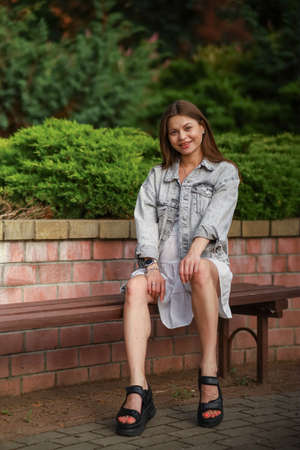 Gorgeous young pregnant woman in fashion jeans clothes in stylish dress has a good time in the park. Attractive girl model in casual outfit.の写真素材