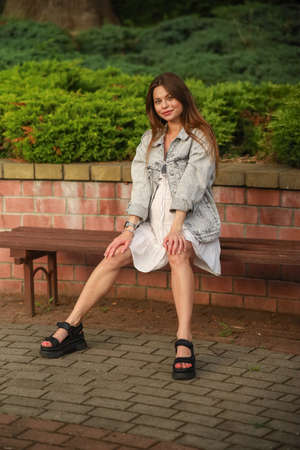 Gorgeous young pregnant woman in fashion jeans clothes in stylish dress has a good time in the park. Attractive girl model in casual outfit.の写真素材