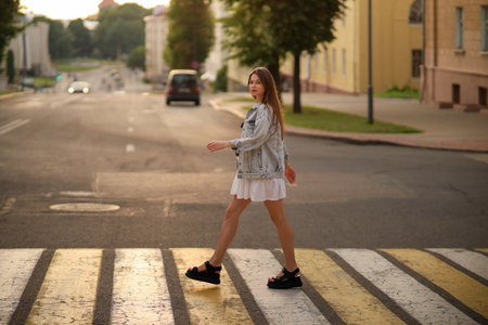 Beautiful happy pregnant woman in a vintage fashion jeans jacket and white dress walking in the city.の写真素材