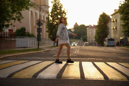 Beautiful happy pregnant woman in a vintage fashion jeans jacket and white dress walking in the city.の写真素材