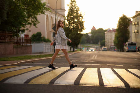 Beautiful happy pregnant woman in a vintage fashion jeans jacket and white dress walking in the city.の写真素材