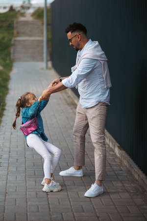 Father and daughter are walking together. Stylish young father having fun with his teenage daughter, the concept of a happy family.の写真素材