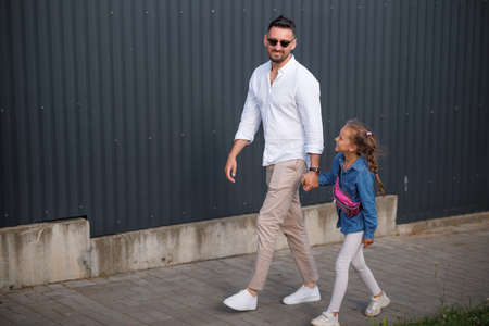 Father and daughter are walking together. Stylish young father having fun with his teenage daughter, the concept of a happy family.の写真素材