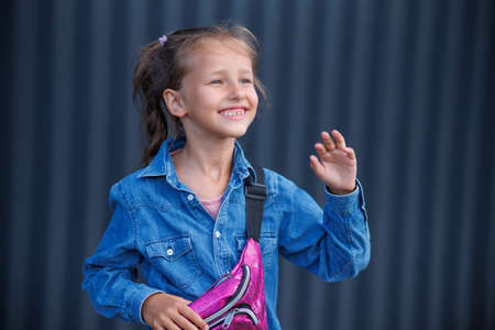 A cute smiling girl in a denim shirt poses on a dark background.の写真素材