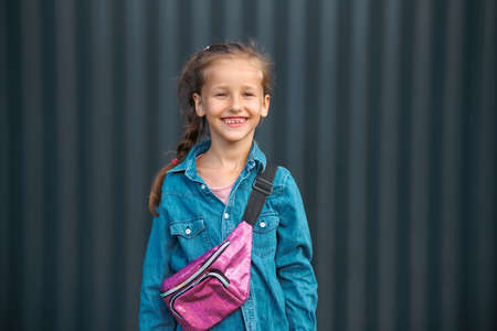 A cute smiling girl in a denim shirt poses on a dark background.の写真素材