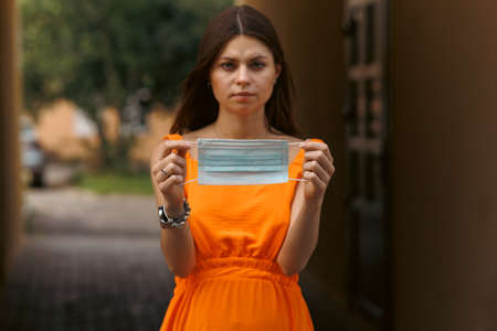 A young girl holds a medical mask in her hands. Suggests wearing a protective mask to protect against the virus.の写真素材