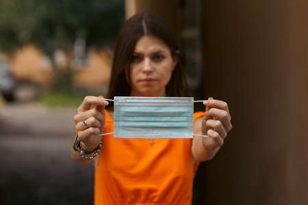 A young girl holds a medical mask in her hands. Suggests wearing a protective mask to protect against the virus.の写真素材