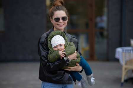 Young mother with her baby on the street in the city in autumnの写真素材