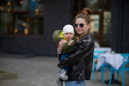 Young mother with baby on the streets of the city in the eveningの写真素材