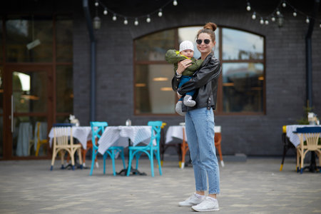 Young mother with a baby in her arms on the background of a cafeの写真素材