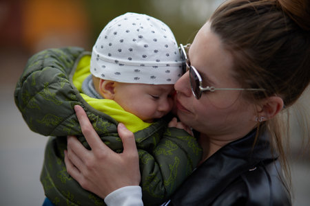Mother kissing her newborn baby boy in the park. Focus on the babyの写真素材