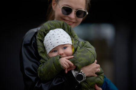 Young mother with her baby boy in a sling on the street.の写真素材