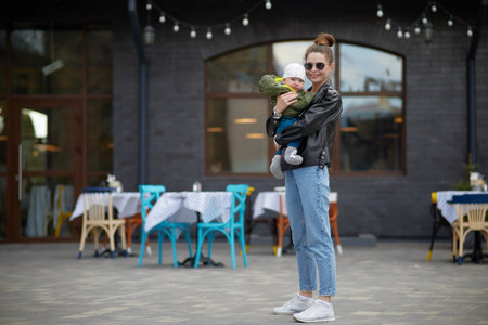 Young mother with a baby in her arms on the background of the cafeの写真素材