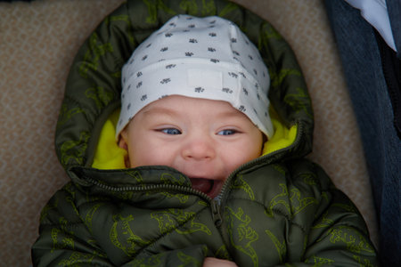 Cute newborn baby boy with blue eyes in a green down jacketの写真素材