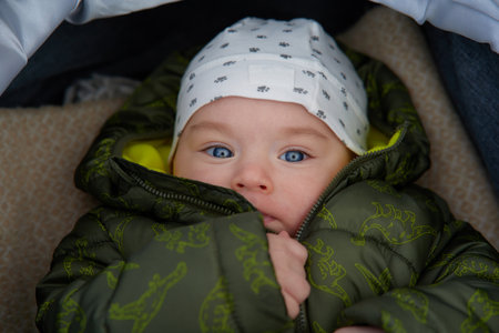 Portrait of a cute baby boy with blue eyes in a green jacketの写真素材