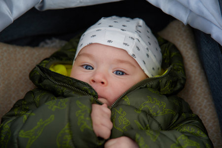 Cute newborn baby boy with blue eyes in a green jacket.の写真素材