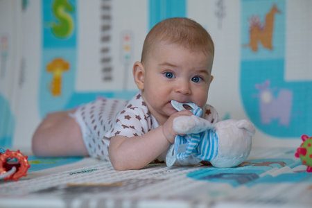 Cute baby girl lying on the floor and playing with toys.の写真素材