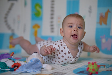 Portrait of a cute baby lying on the floor and playing with toysの写真素材