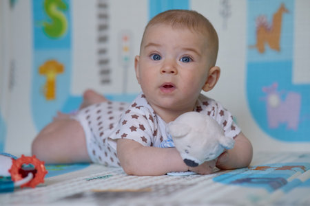 Portrait of a cute baby girl lying on the floor and playing with toysの写真素材