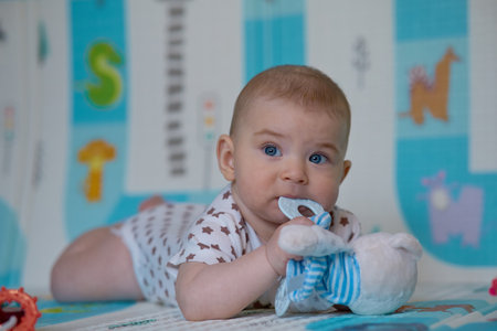 Portrait of a cute baby girl with blue eyes lying on the floorの写真素材
