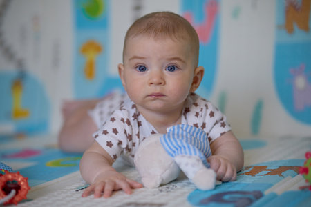 Portrait of cute baby girl with blue eyes lying on the floorの写真素材