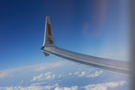 Aircraft wing in the blue sky with white clouds on a sunny dayの写真素材